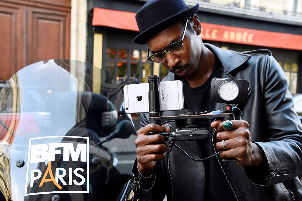 A journalist holds a shoulderpod, a tripod mount adapter with an Iphone smartphone
