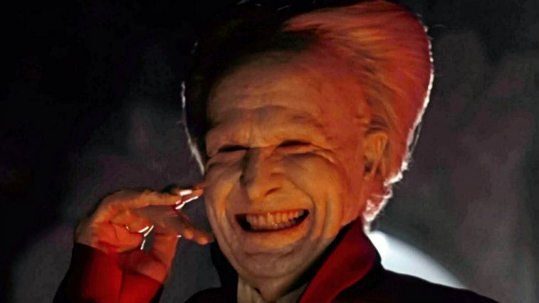 Gary Oldman with his hand to his face, smiling ear to ear in Dracula