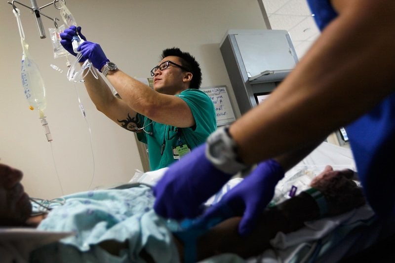 A registered nurse hangs an I.V. bag for a patient