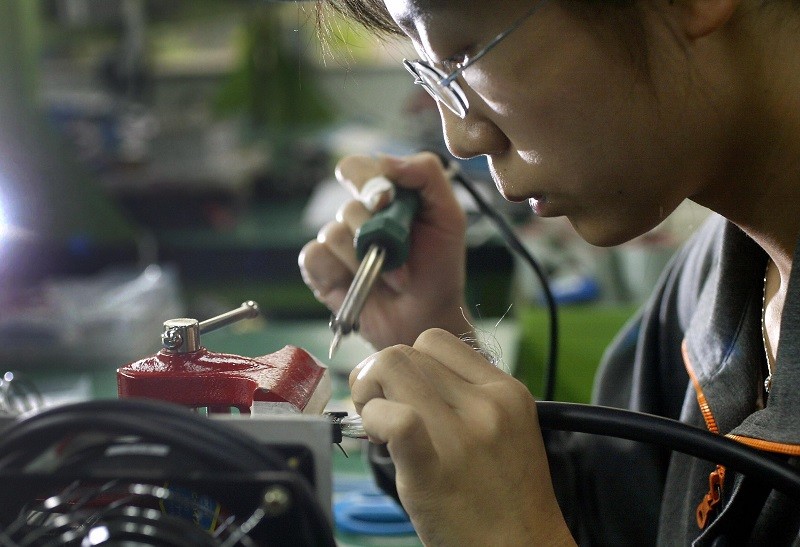A factory worker makes parts at a joint venture Chinese and Japanese electronics firm 