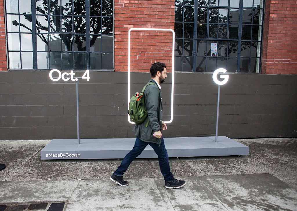 A pedestrian walks by a sign outside an event by Google