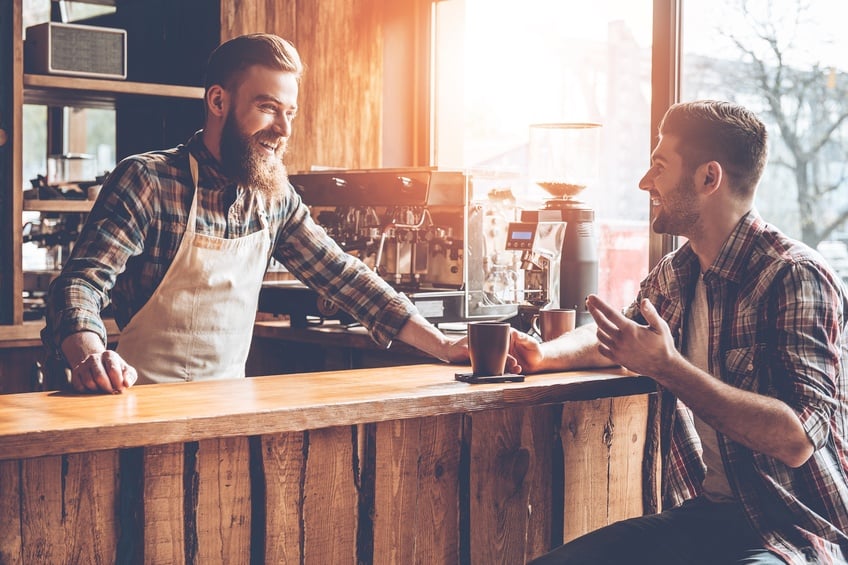 Barista and his customer discussing something with smile