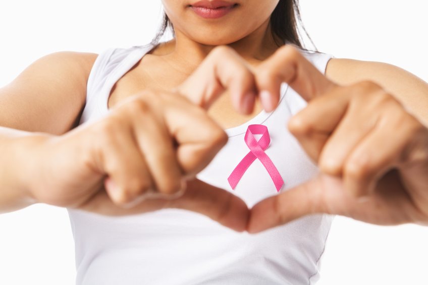 Woman with her fingers in the shape of a heart around the pink breast cancer ribbon Woman with her fingers in the shape of a heart around the pink breast cancer ribbon