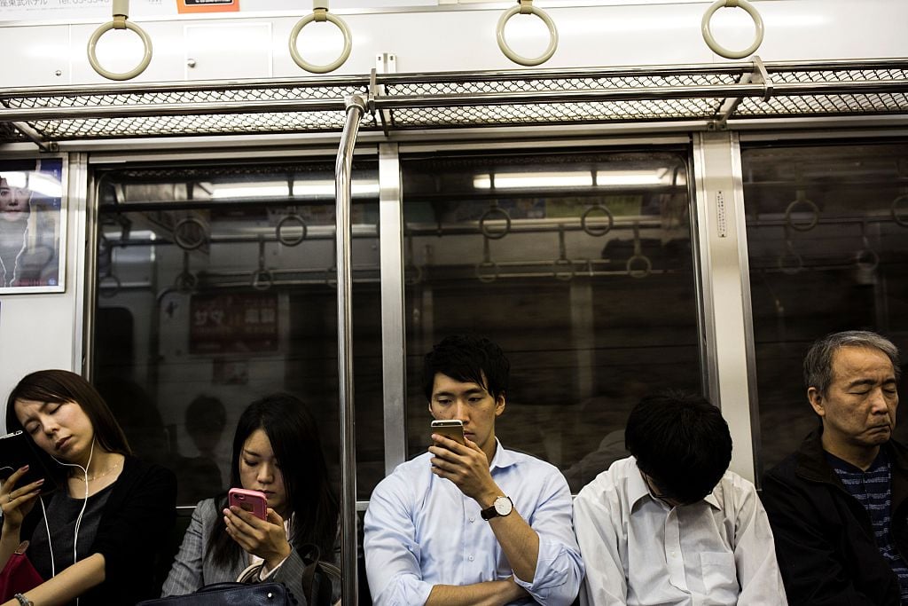 Japanese commuters check their smart phones in a subway