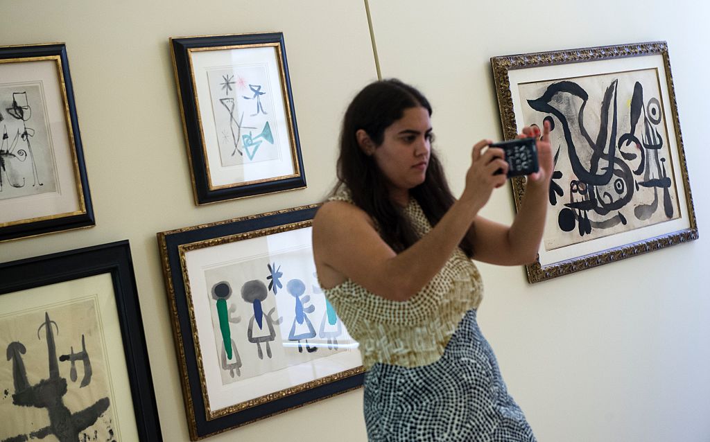 A visitor takes pictures with her smartphone past a piece of the exhibition