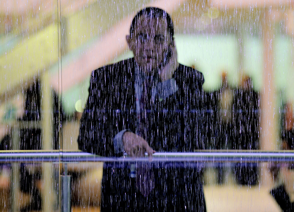 A man speaking on his phone looks through a window pane