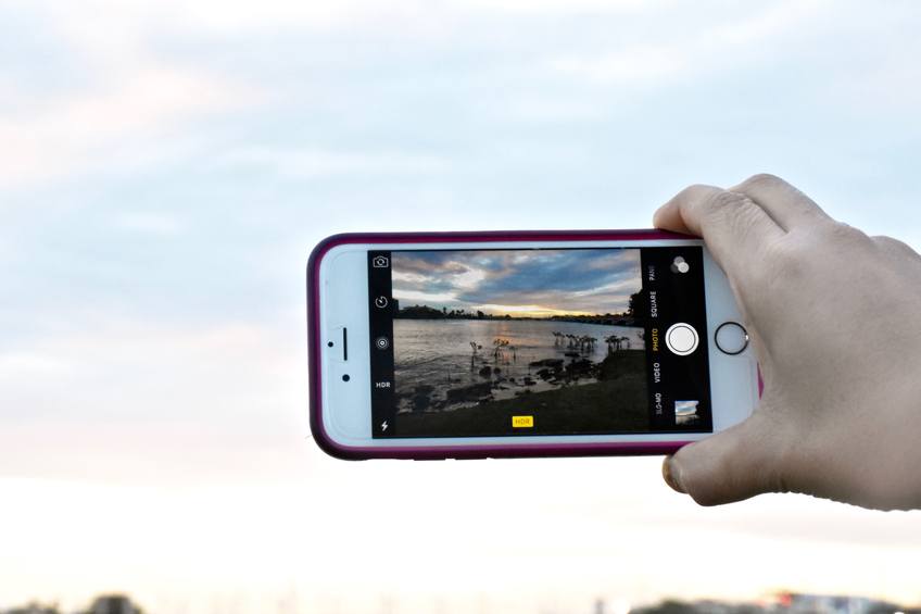 A person taking a picture of the sunset with an iPhone