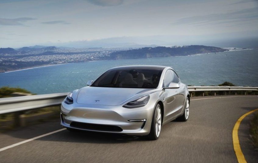 Road shot of silver Tesla Model 3 on California coast
