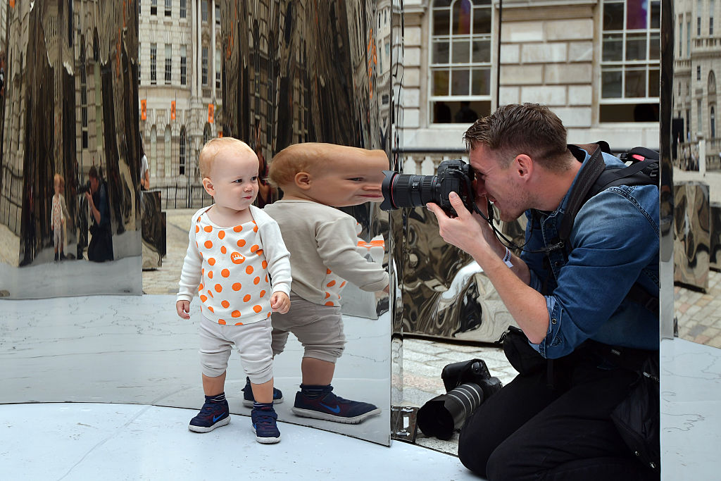 17-month-old Hugo Baumann Malcolmson is reflected as he is photographed