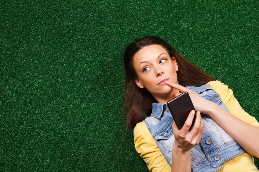 young woman is lying on the grass and thinking