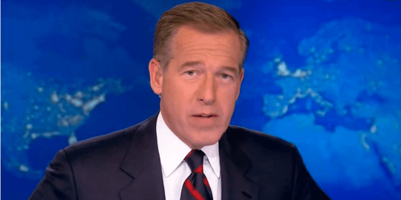 Brian Williams sits in a suit