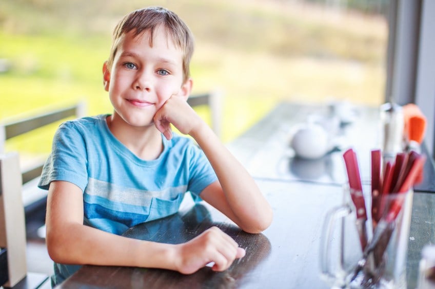 cute boy sitting at a table and smiling