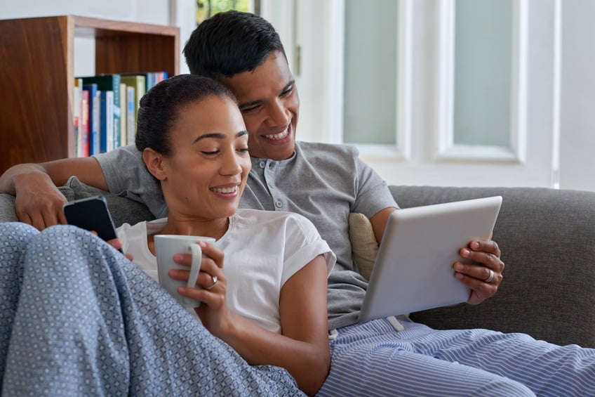 smiling couple with tablet computer on sofa
