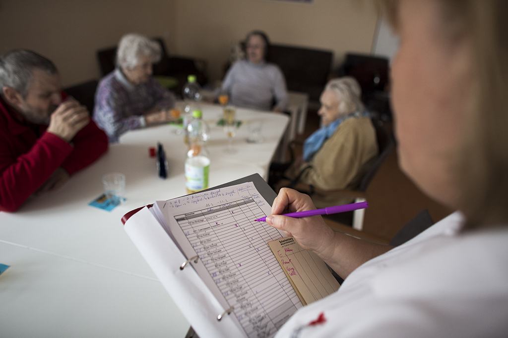 a nurse takes notes as senior patients sit