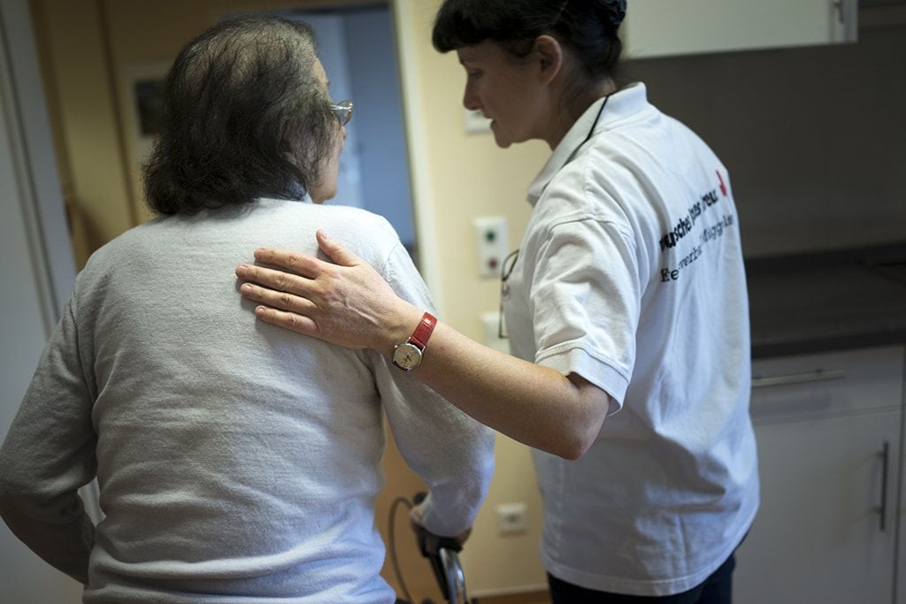 care giver assisting a woman with a walker