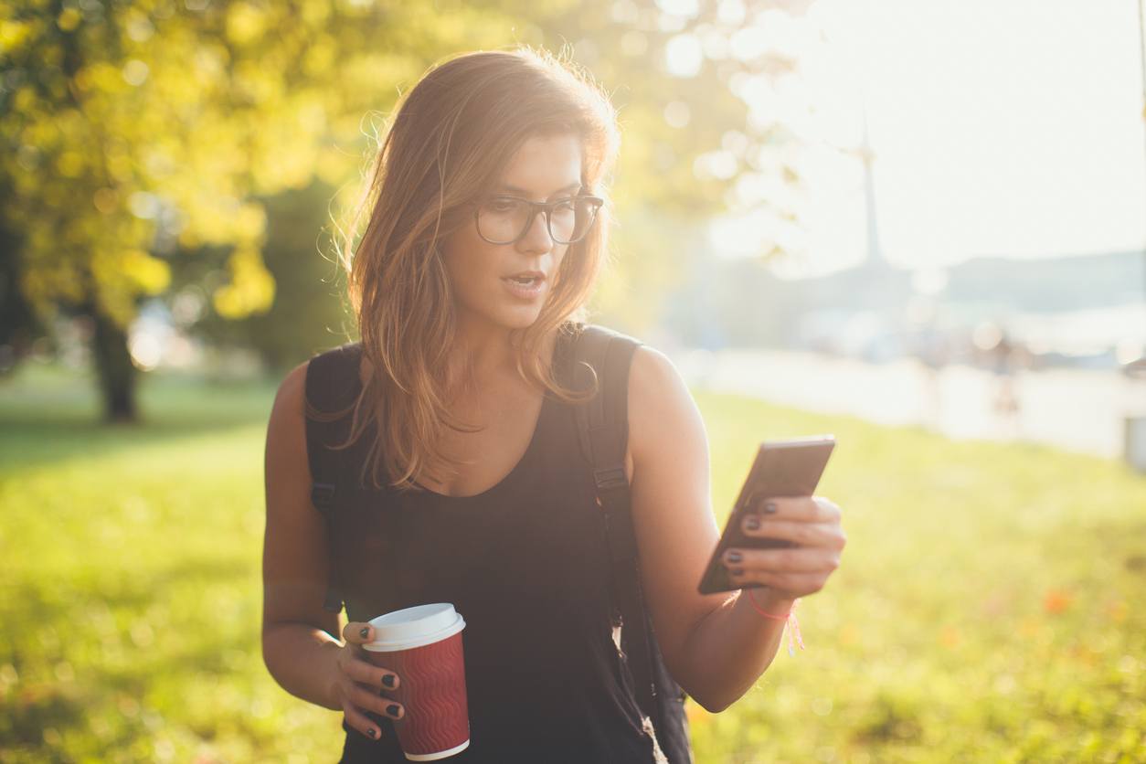 young woman holding phone and coffee