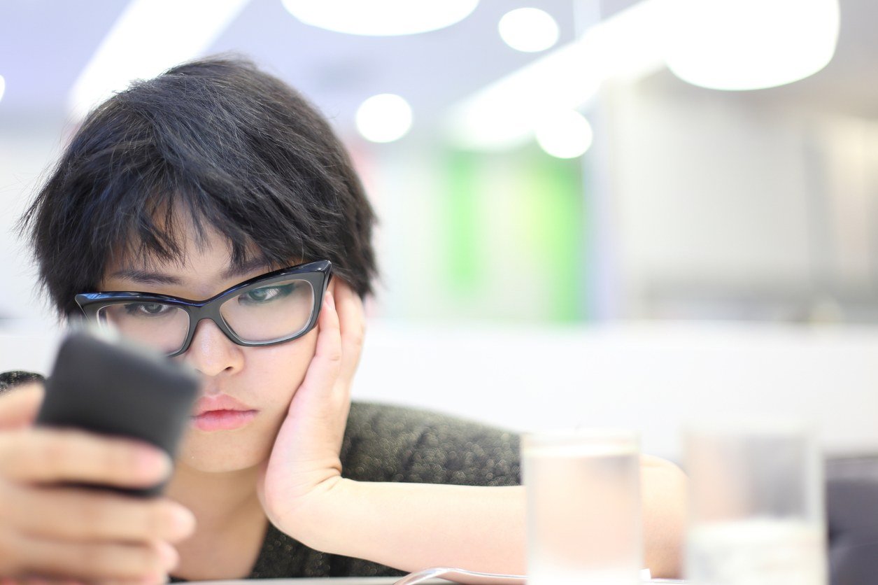 Girl looking at mobile phone and feeling unhappy