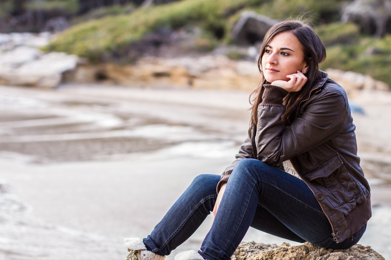 woman wearing jeans and jacket on the beach