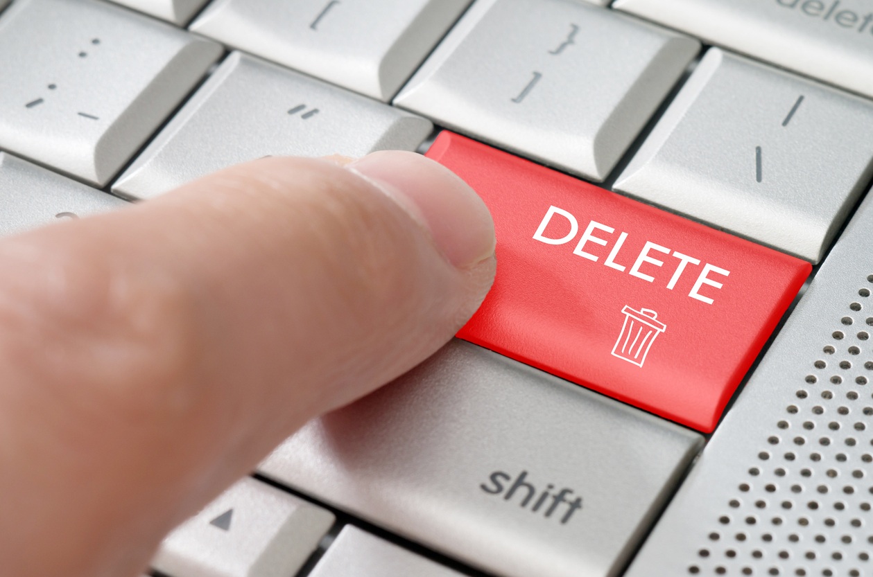 male finger pointing delete key on a metallic keyboard