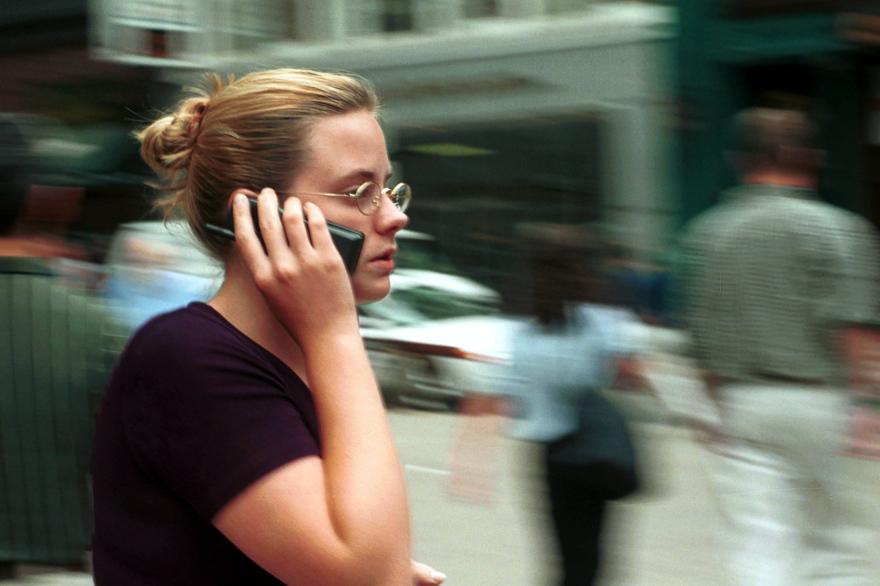 A woman uses her cell phone while walking down the street in Boston MA