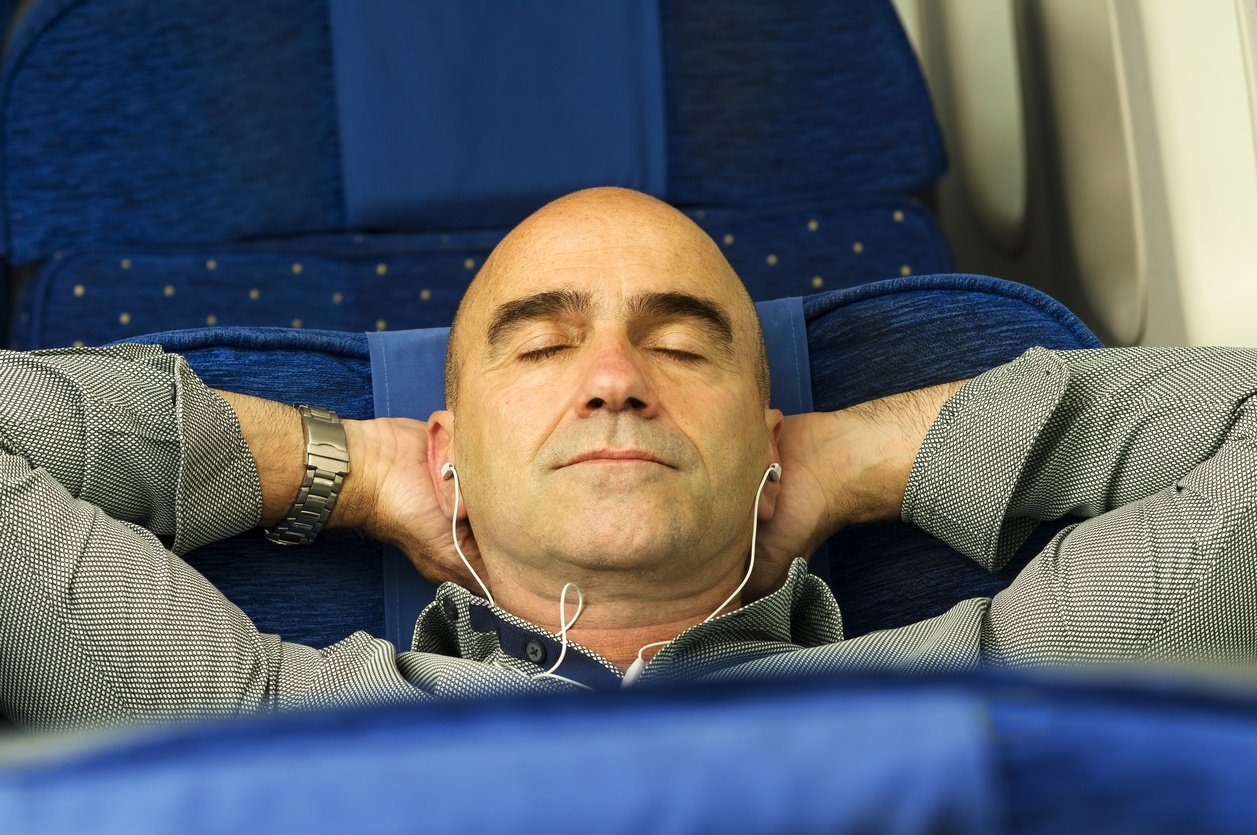 man passenger in airplane using mobile smart device with headphones