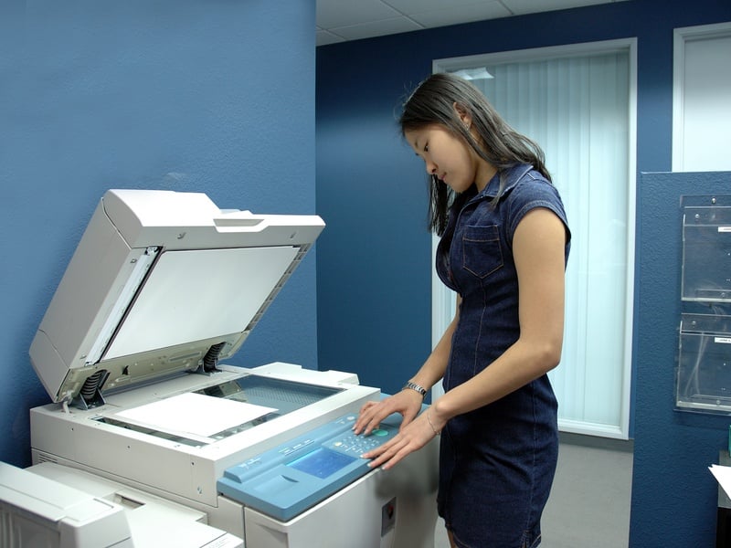 A young Asian girl working on copying machine