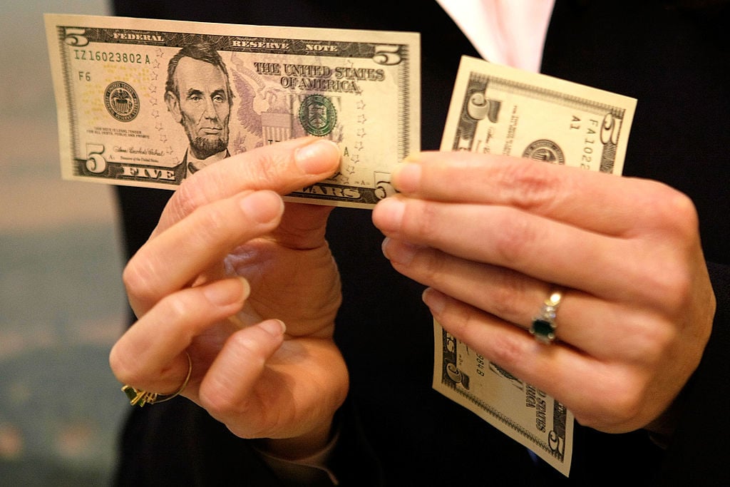 woman holds a $5 bill