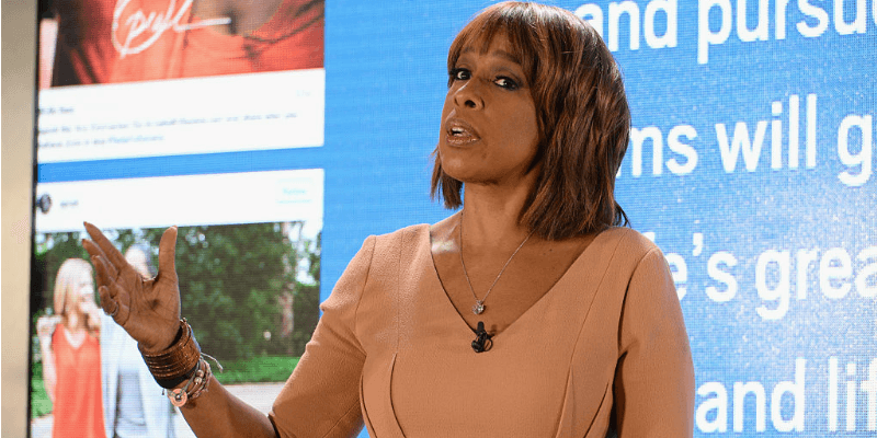 Gayle King standing and waving her hand while at a presentation. Gayle King standing and waving her hand while at a presentation.