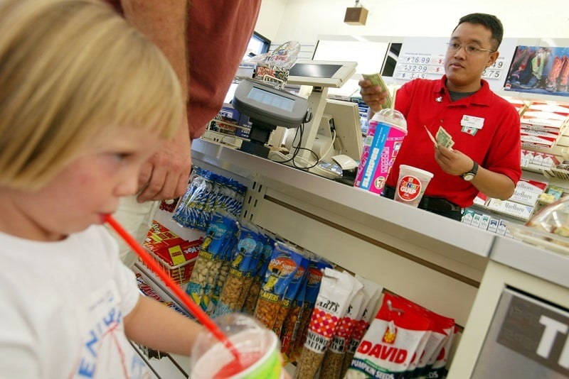 A 7-11 employee sells soda and Slurpees to a man and his children
