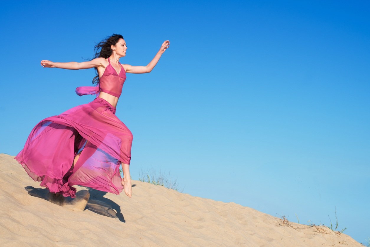 beautiful girl in an airy dress running on sand dunes