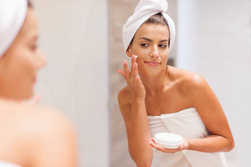 woman applying moisturizer on face