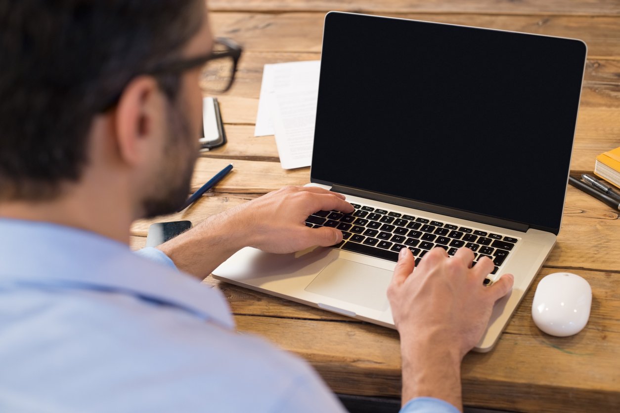 businessman sitting in front of laptop screen