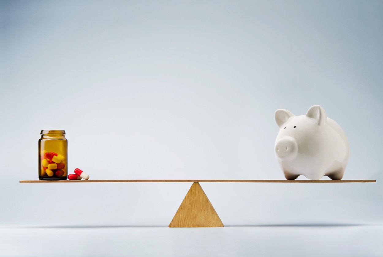 Piggy bank balancing on seesaw against medicine
