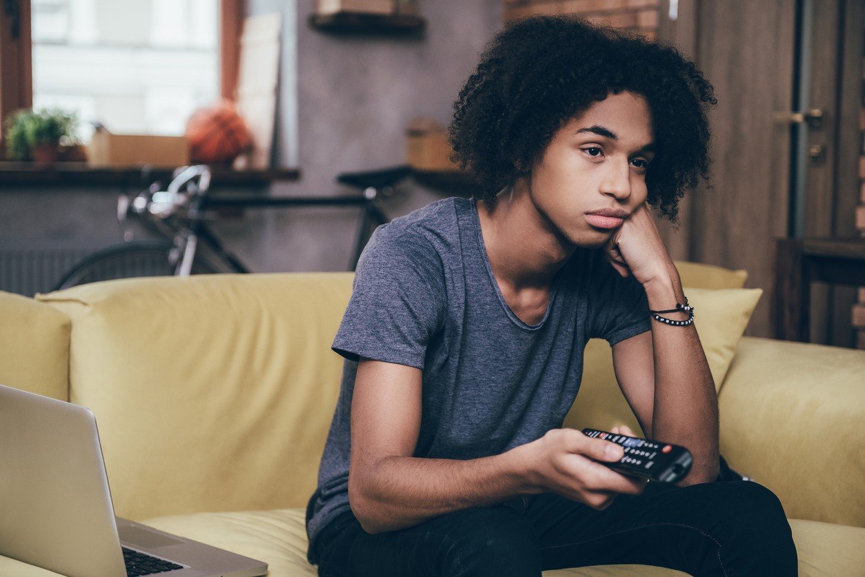 African man holding remote control and looking bored