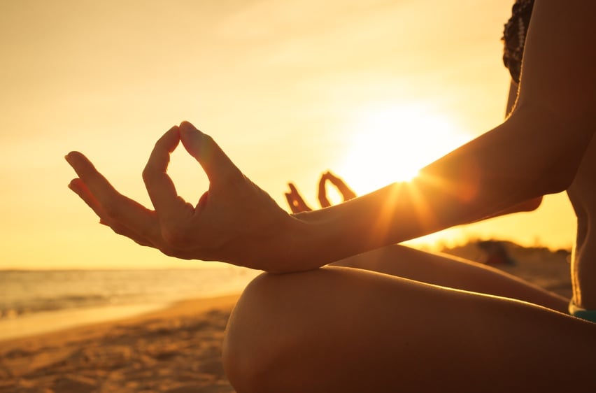 Woman meditating on the beach in front of the sun. Woman meditating on the beach in front of the sun.