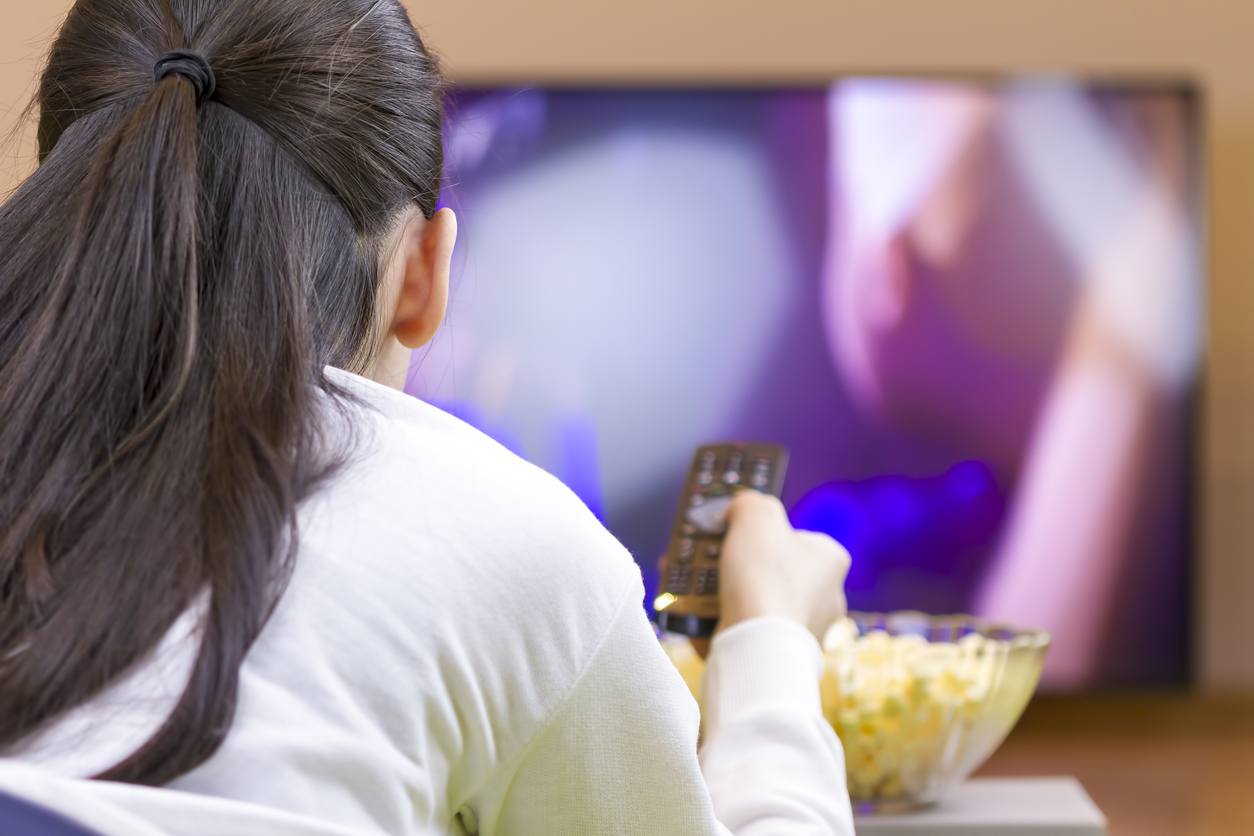 Teenager girl eating and watching tv