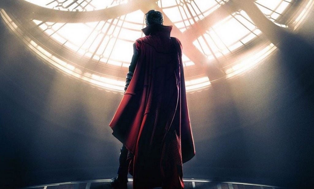 Benedict Cumberbatch stands in front of a window in his cape in a scene from Doctor Strange