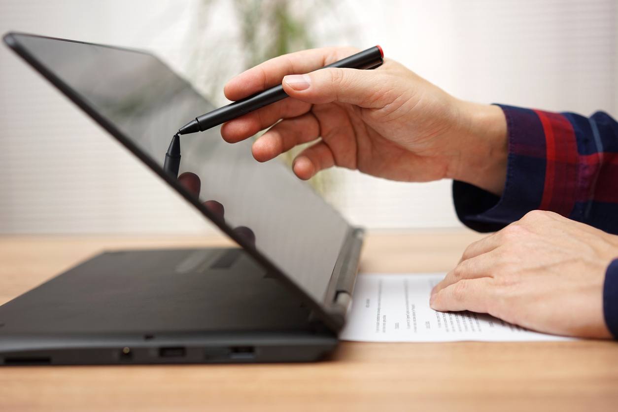 A man is working on touchscreen laptop