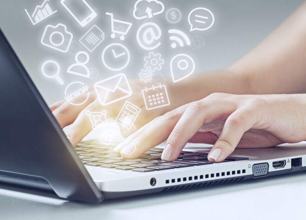 woman typing on laptop computer and media app icons flying