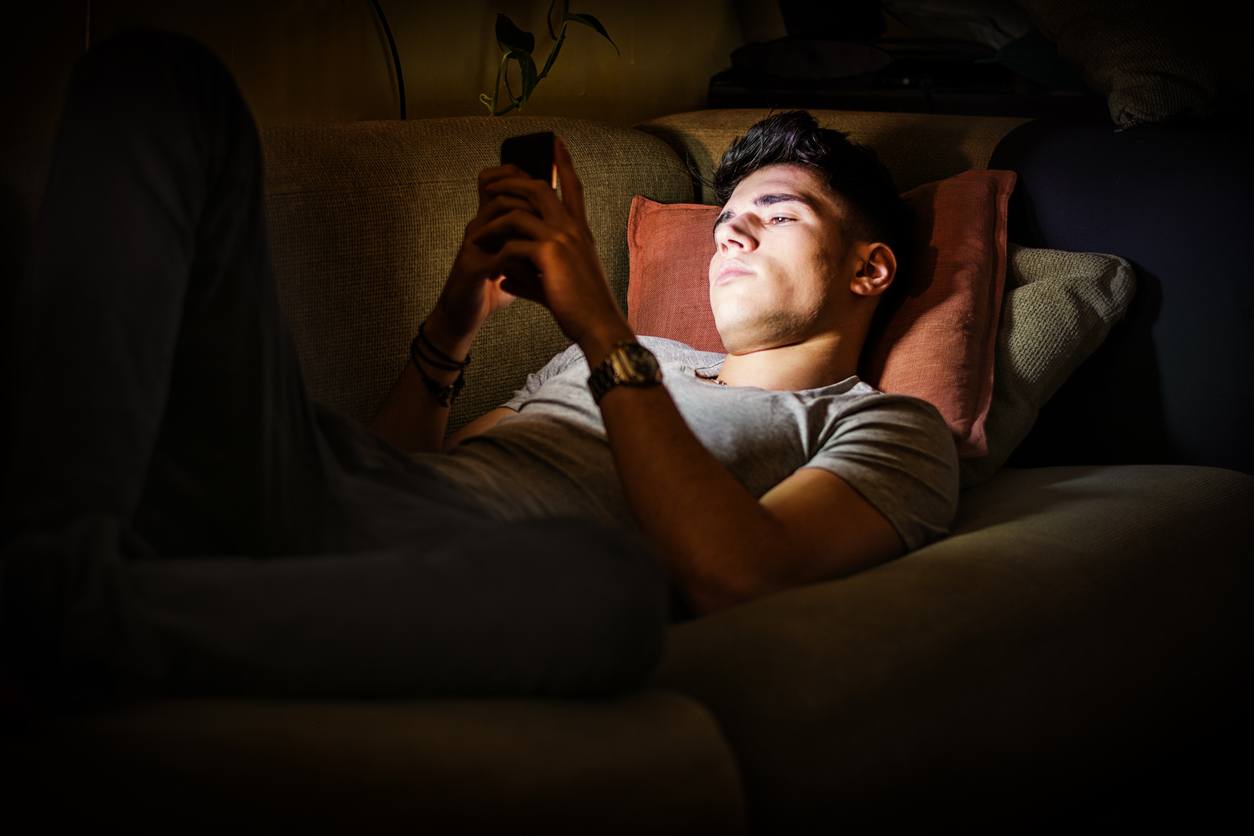Young Man Lying on Sofa at Night and Illuminated by Light