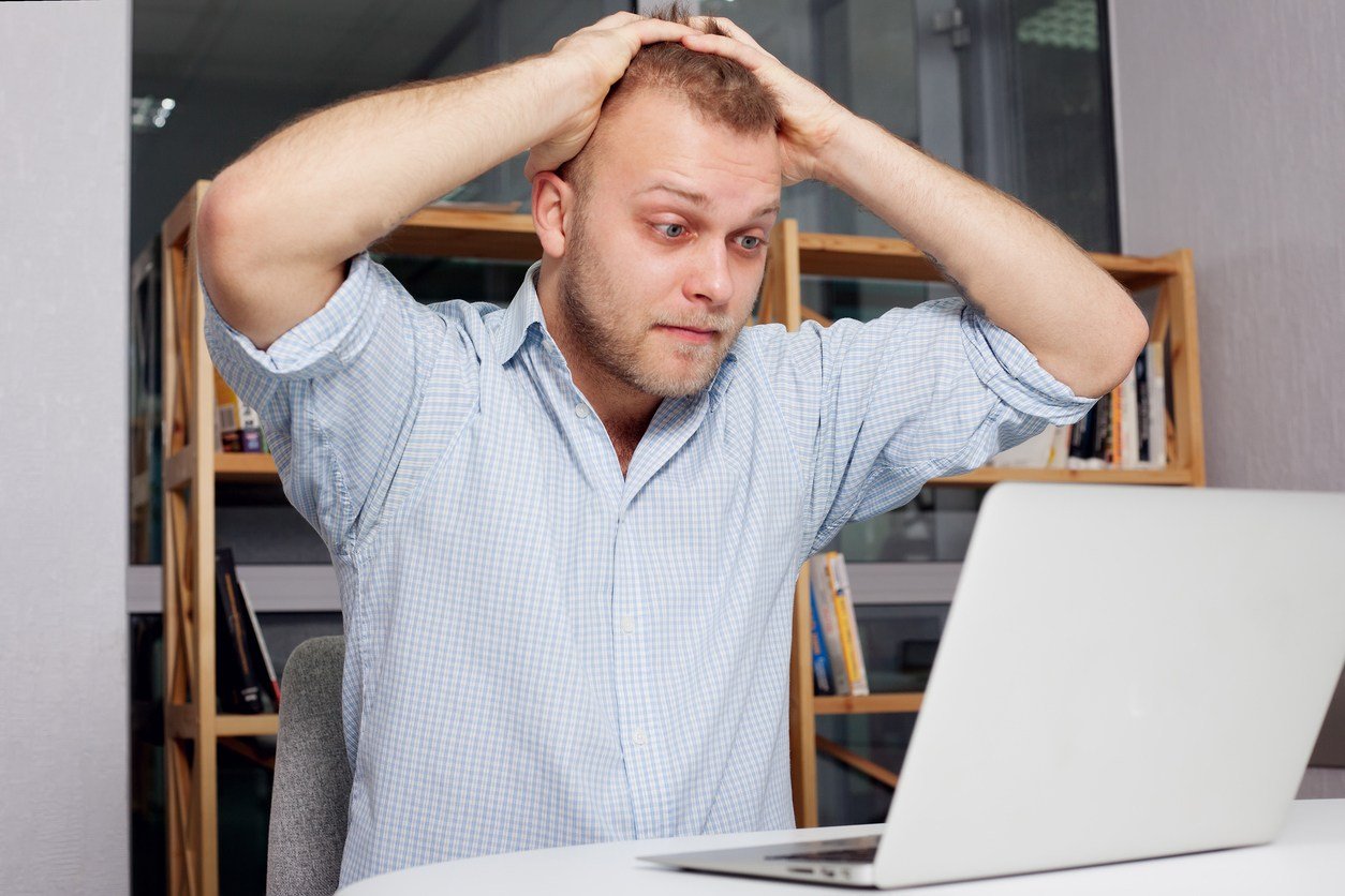 businessman at his desk looking fearfully at a laptop