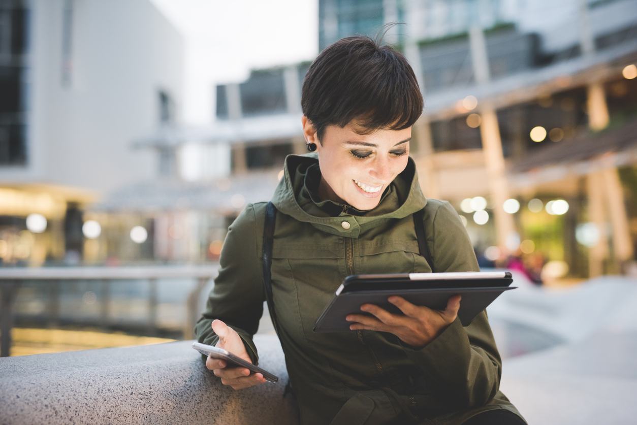 Woman using smartphone and tablet outside