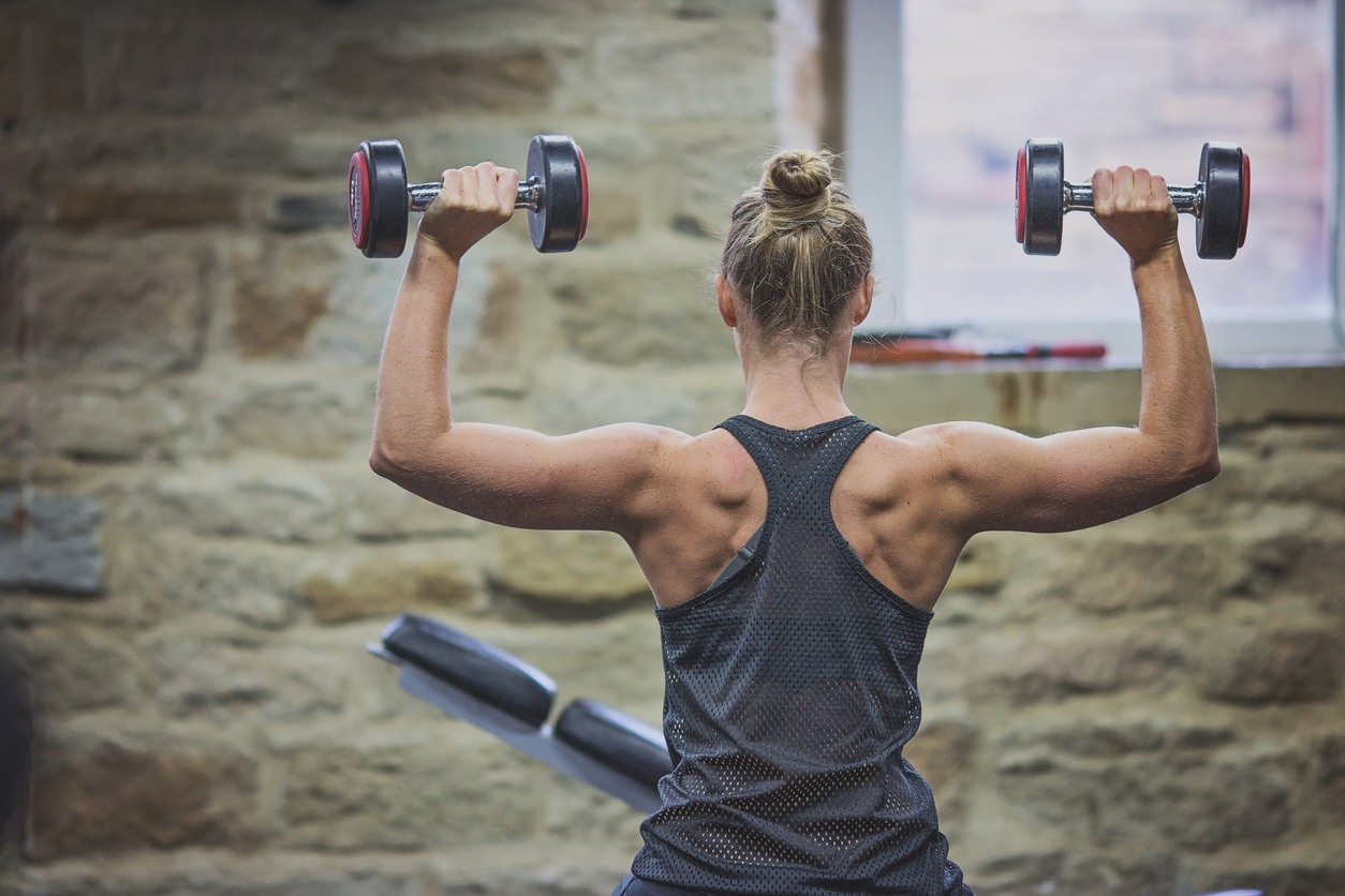 woman holding dumbells above her head