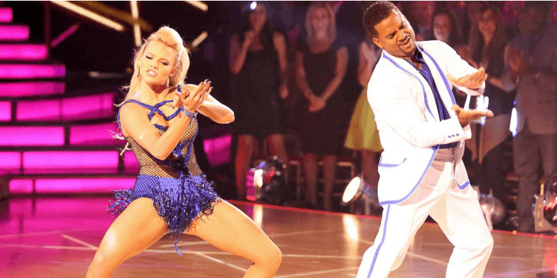 Alfonso Ribeiro dances in a white suit next to his partner on the dance floor.