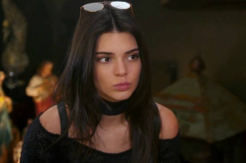 Kendall Jenner wears a black shirt and glasses on his head