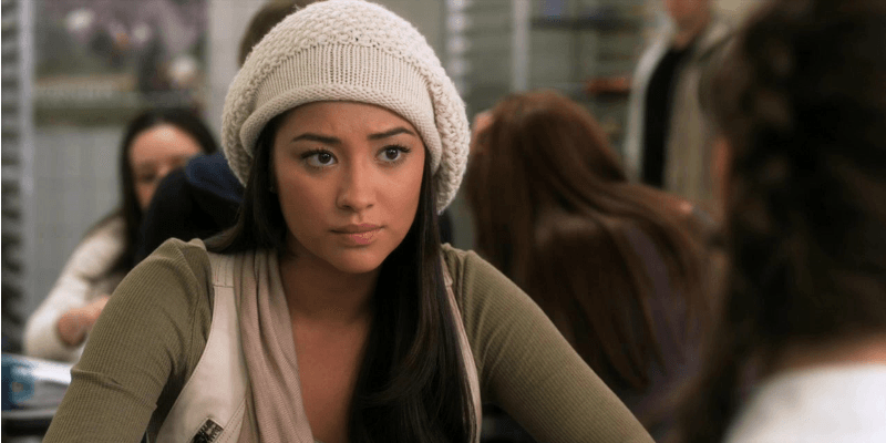 Emily is sitting a lunch room in Pretty Little Liars.