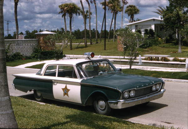 A green and white 1960 Ford Fairlane cop car