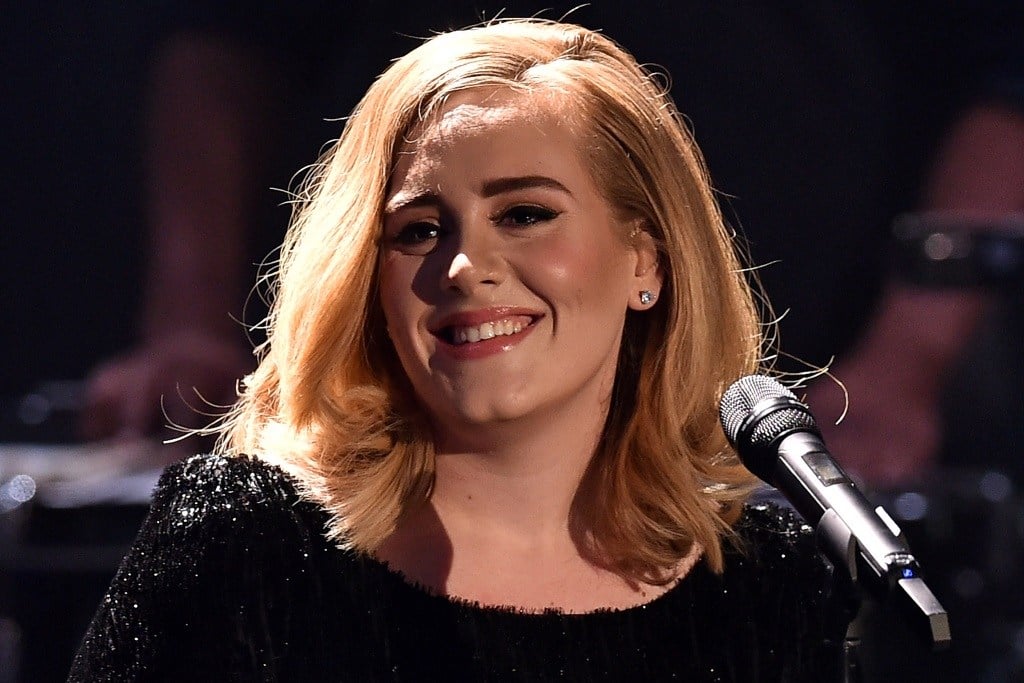 Adele smiles while in front of a microphone. 