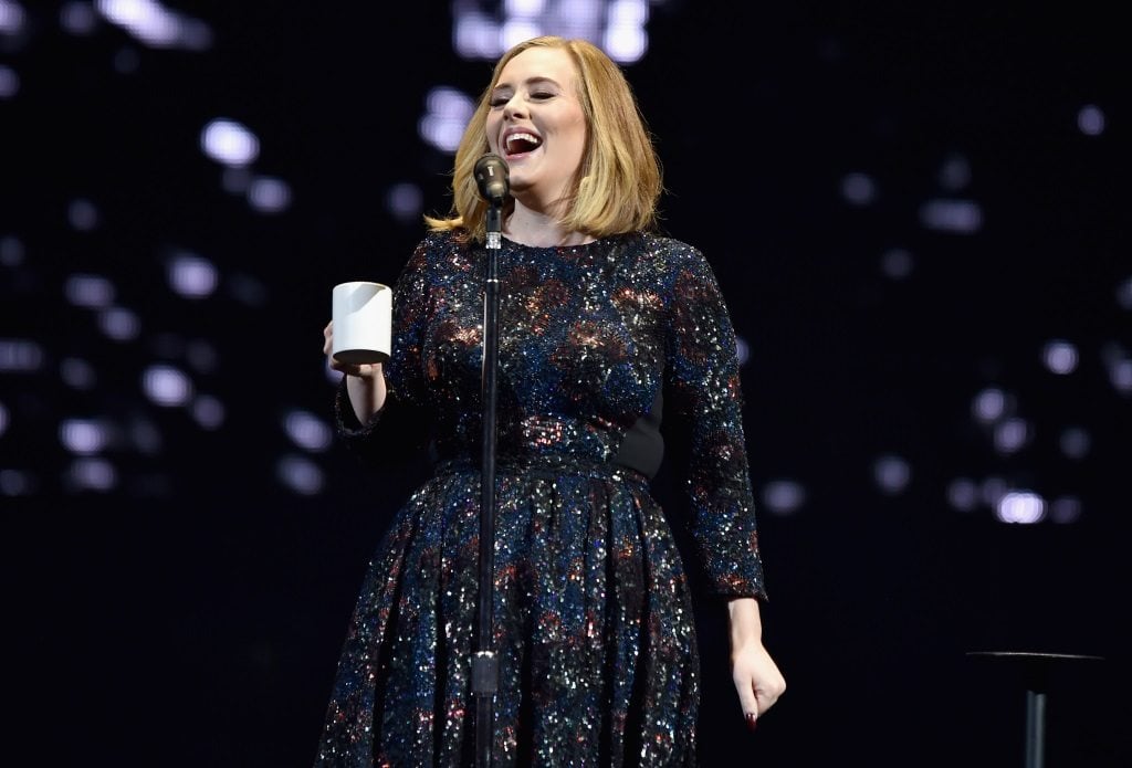 Adele is singing in a black dress on stage.