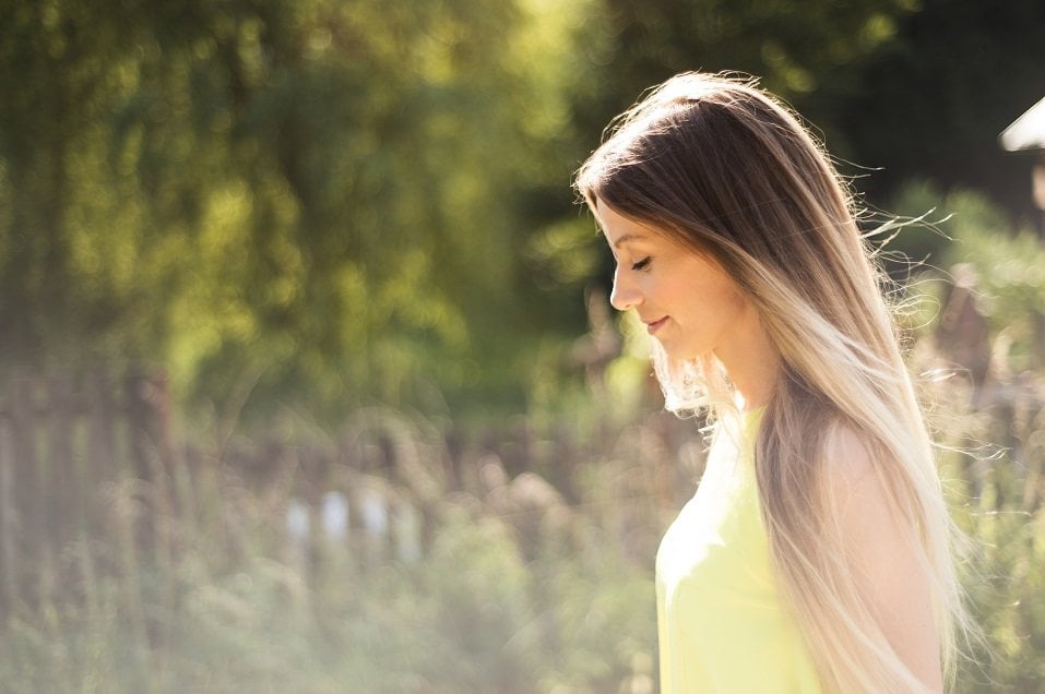 young woman with long blowing blonde hair in neon yellow tank top
